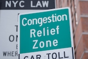 Signs, including some advising drivers of congestion pricing tolls, are displayed near the exit of the Lincoln Tunnel in New York. A federal court judge heard arguments Tuesday to bar the USDOT
from shutting down the program until a lawsuit is
heard.